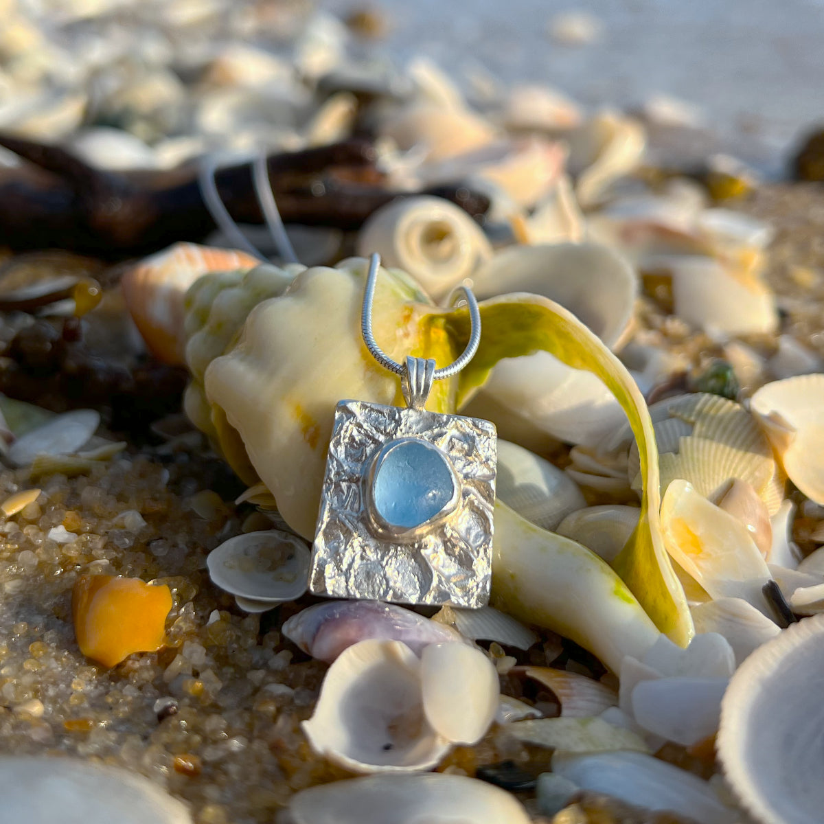 Cornflower blue sea glass set on a mermaid scale textured backing pendant by Mornington Sea Glass. Comes with a 40 or 45cm sterling silver chain.