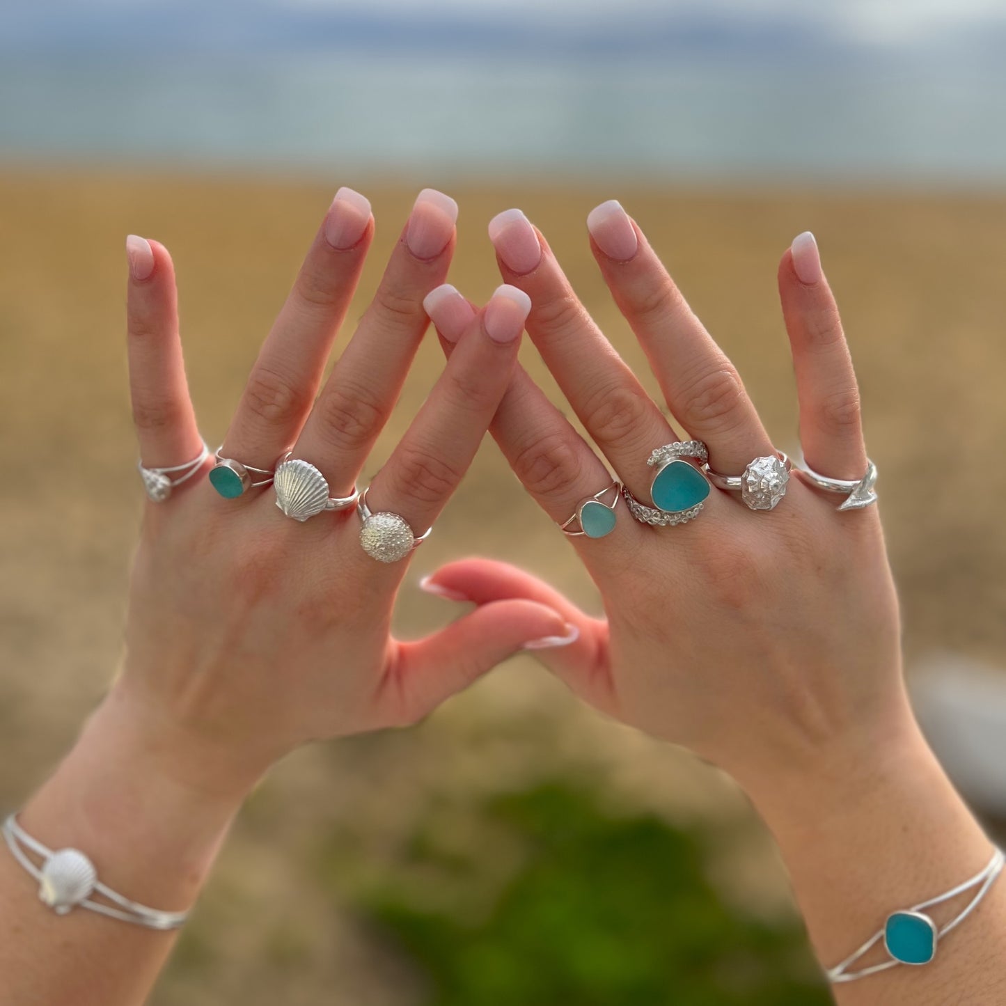 Hands modelling sea glass and cast silver shell rings and bangles by Mornington Sea Glass