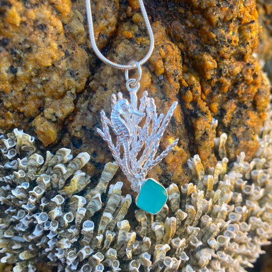 Sterling silver necklace of a cast silver seahorse hiding in coral with a aqua sea glass treasure. Hangs on a 40 or 45cm sterling silver chain.