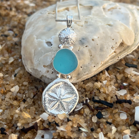 Sterling silver necklace of cast silver sea biscuits and urchin shells and blue sea glass. Hangs on a 40 or 45cm sterling silver chain. By Mornington Sea Glass.