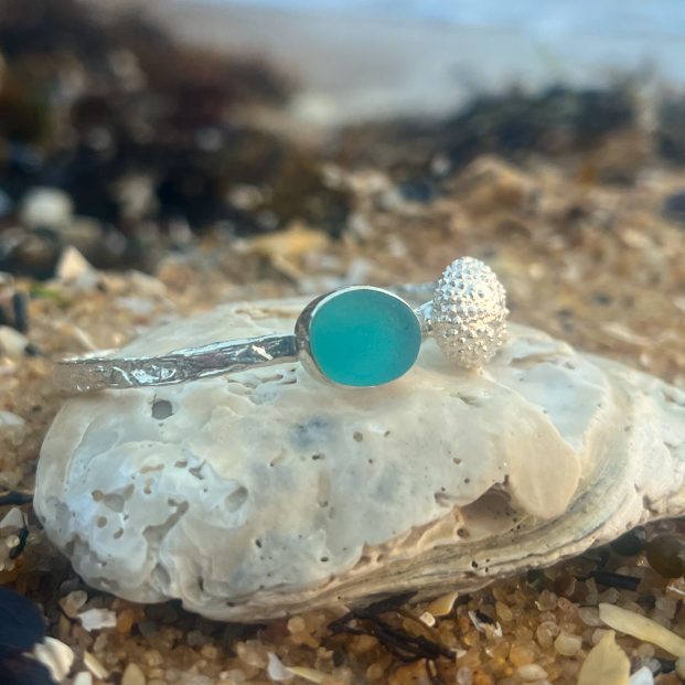 Sterling silver crushed texture cuff featuring a cast silver sea urchin shell and an ocean teal sea glass gem. 60cm diameter with a 3cm opening.By Mornington Sea Glass