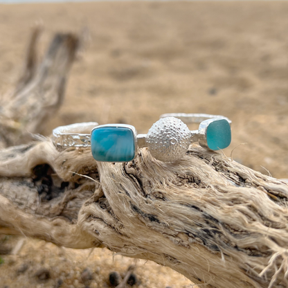 Sterling silver crushed texture cuff featuring a cast silver sea urchin shell, an ocean teal sea glass gem and natural Larimar.. 60cm diameter with a 3cm opening.By Mornington Sea Glass