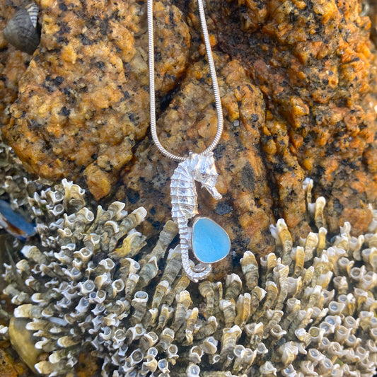 Sterling silver necklace of a small cast silver seahorse with a tiny blue sea glass treasure. Hangs on a 40 or 45cm sterling silver chain. By Mornington Sea Glass.