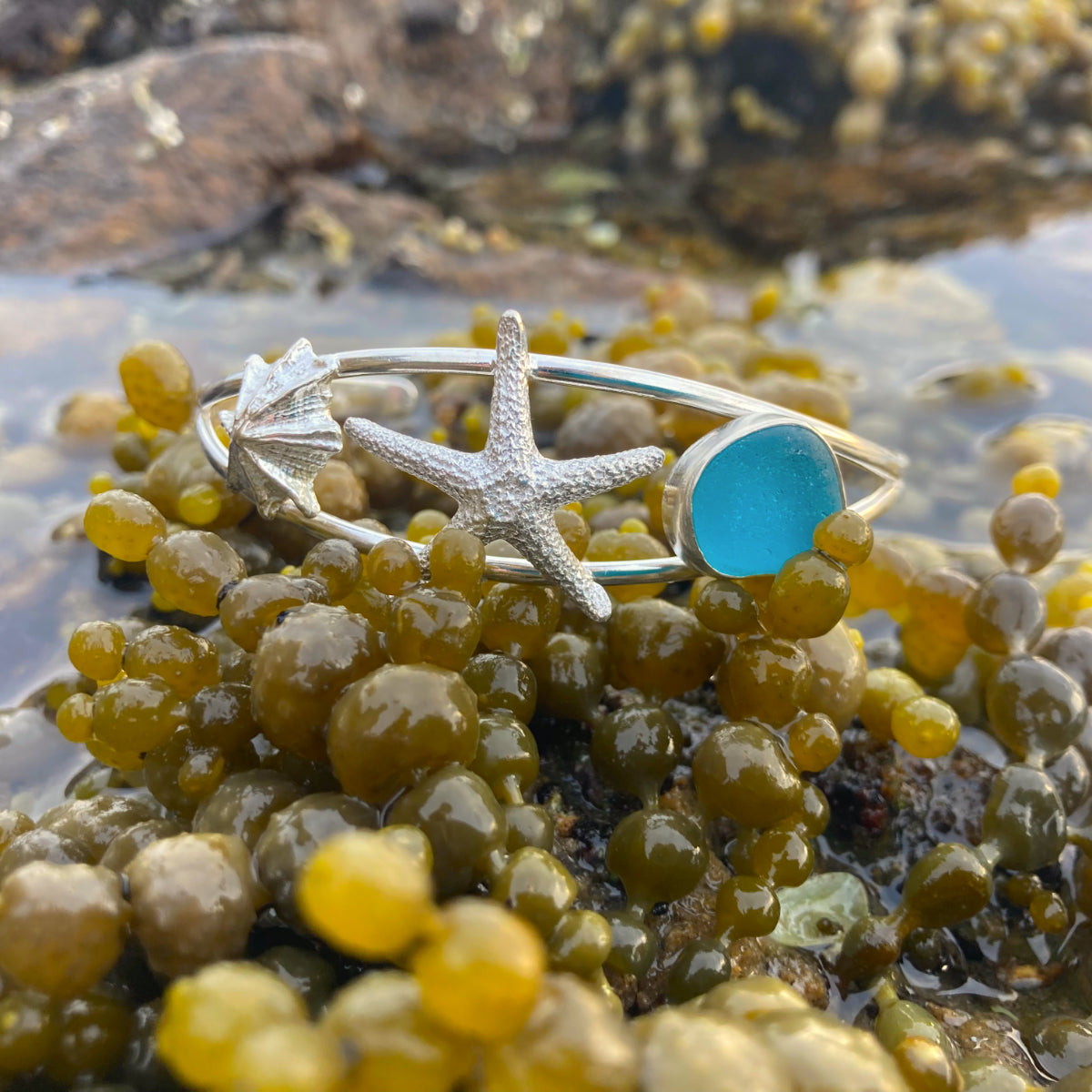 Sterling silver split centre cuff featuring a cast silver limpet shell and sea star as well as ocean teal sea glass gem. 60cm diameter with a 3cm opening. By Mornington Sea Glass.