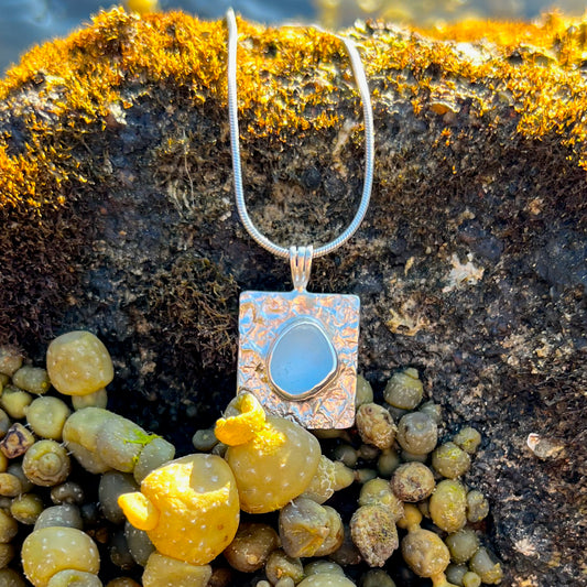 Cornflower blue sea glass set on a mermaid scale textured backing pendant by Mornington Sea Glass. Comes with a 40 or 45cm sterling silver chain.