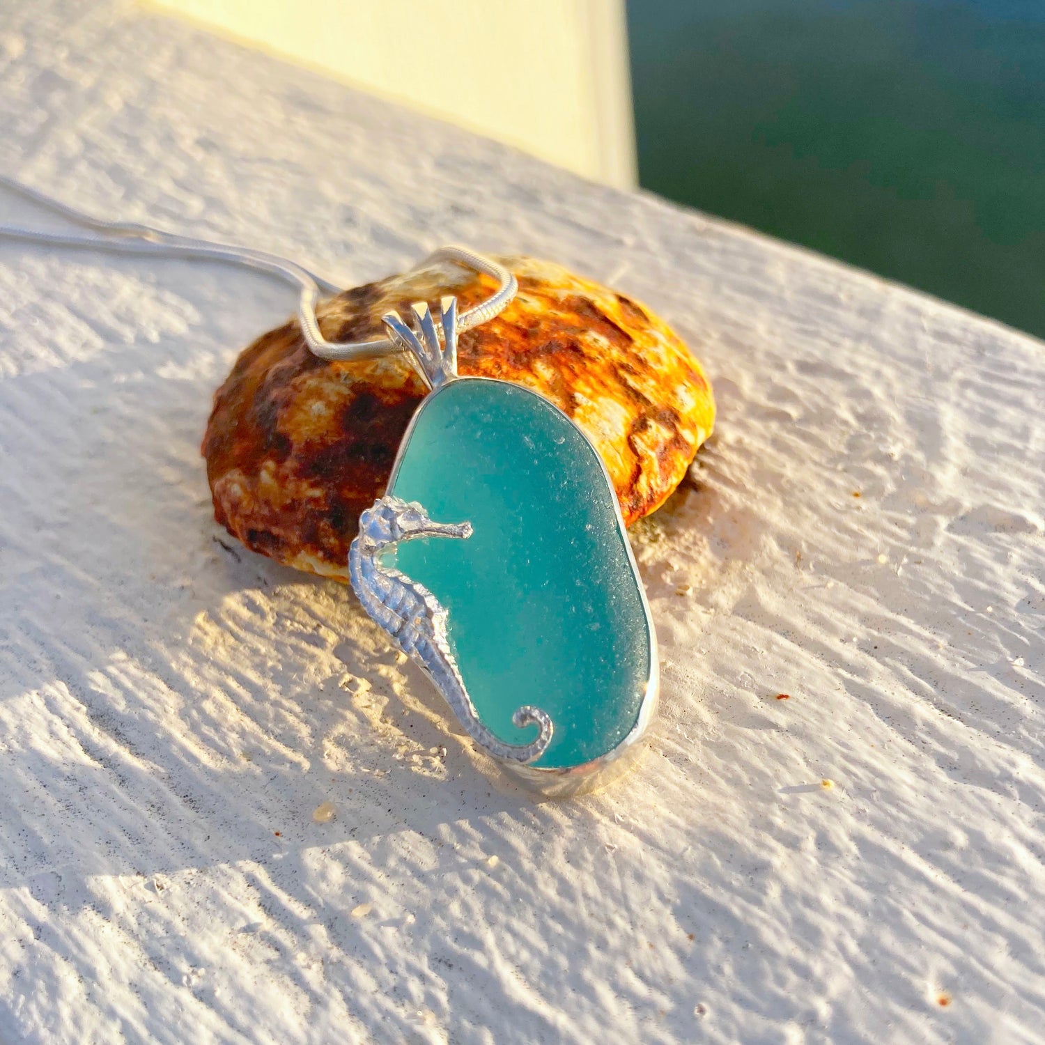 Aqua sea glass pendant with a seahorse by Mornington Sea Glass. Photographed on a pier on the Mornington Peninsula, Victoria, Australia.