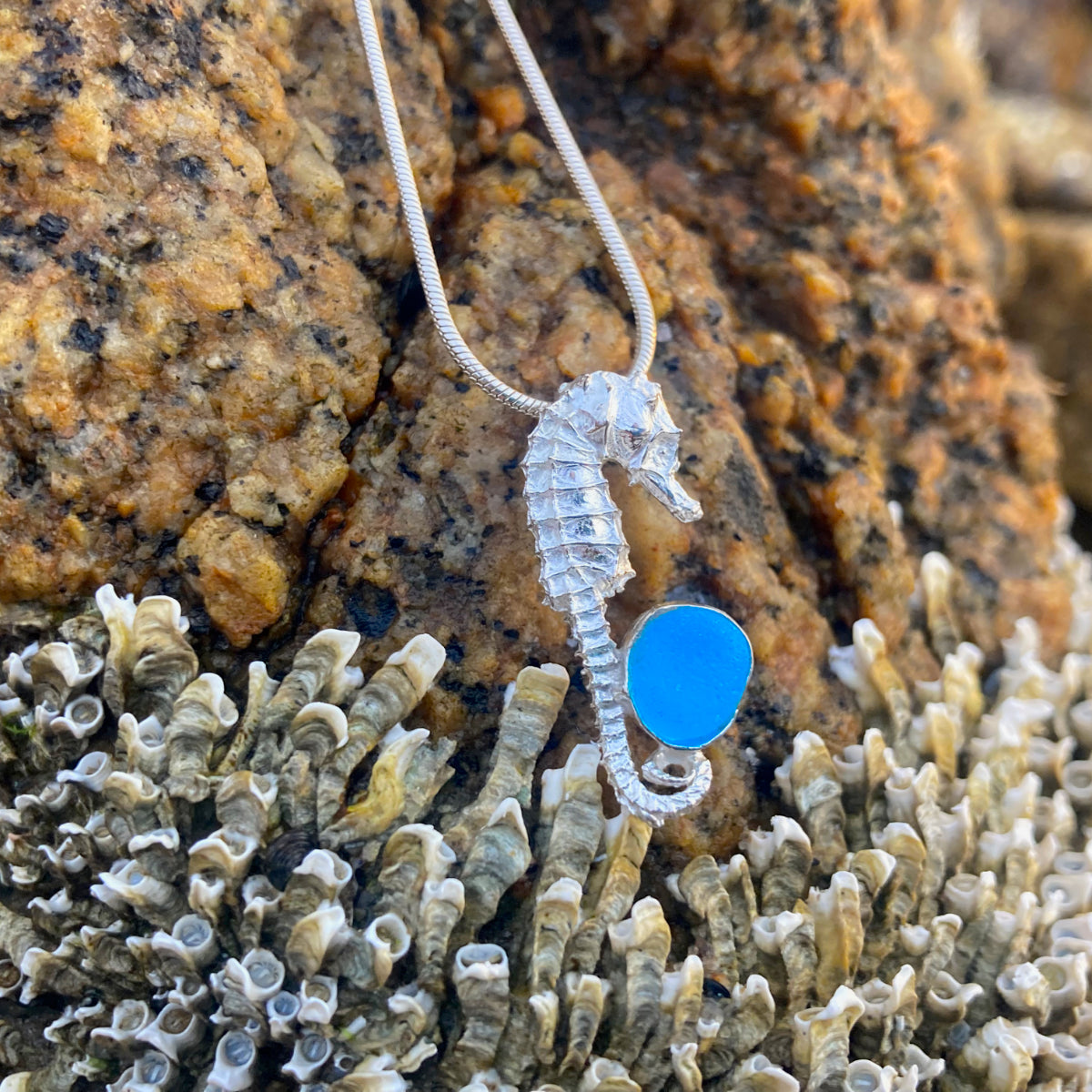 Sterling silver necklace of a small cast silver seahorse with a tiny blue sea glass treasure. Hangs on a 40 or 45cm sterling silver chain. By Mornington Sea Glass.