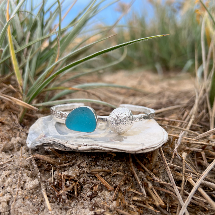 Sterling silver crushed texture cuff featuring a cast silver sea urchin shell and an ocean teal sea glass gem. 60cm diameter with a 3cm opening.By Mornington Sea Glass