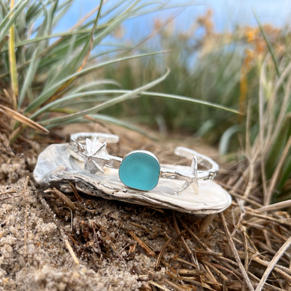 Sterling silver crushed texture cuff featuring a cast silver limpet shell, sea star  and an aqua sea glass gem. 60cm diameter with a 3cm opening.By Mornington Sea Glass