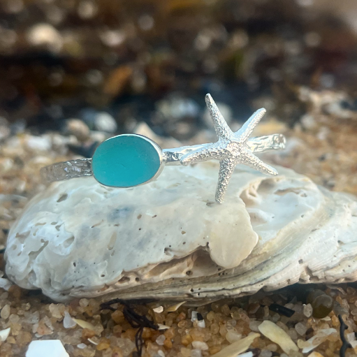 Sterling silver crushed texture cuff featuring a cast silver starfish and a blue sea glass gem. 60cm diameter with a 3cm opening.By Mornington Sea Glass